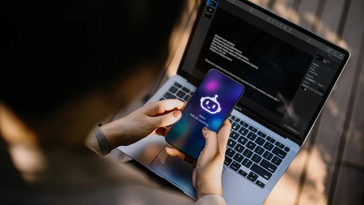 Businesswoman using Chatting AI chatbot virtual assistance app on smartphone to assist her while working on laptop in office park. Using AI technology at work. Online robot system. Concept of VR and AR technologies. People, AI, innovation and technology